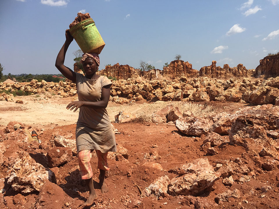 Woman walking and holding basket of coral stone on her head