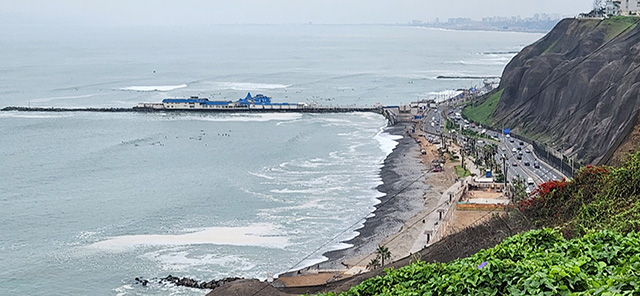 Coastal Line of Lima, ocean waves crashing against the beach near busy road