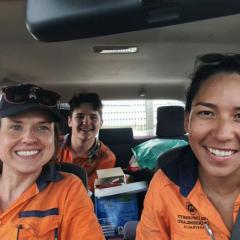 People wearing fluro orange PPE in a car smiling to camera 