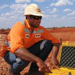 Indigenous Australian worker in orange high visibility clothing and helmet