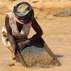 Female Madagascar miner sieving gems from soil and dirt